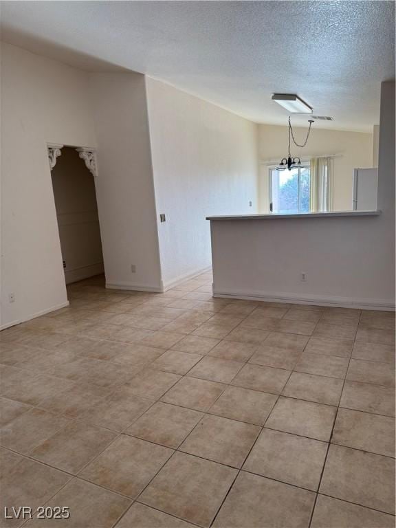 empty room with a textured ceiling, a notable chandelier, and baseboards