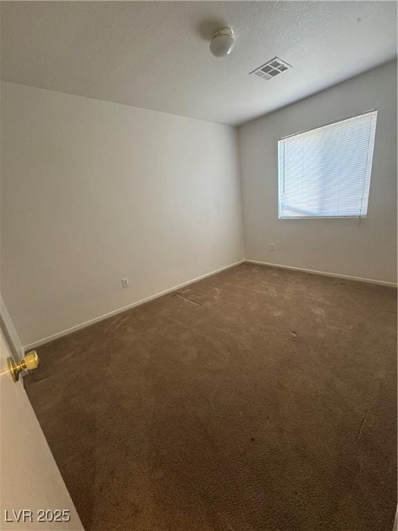 empty room with dark carpet, baseboards, and visible vents