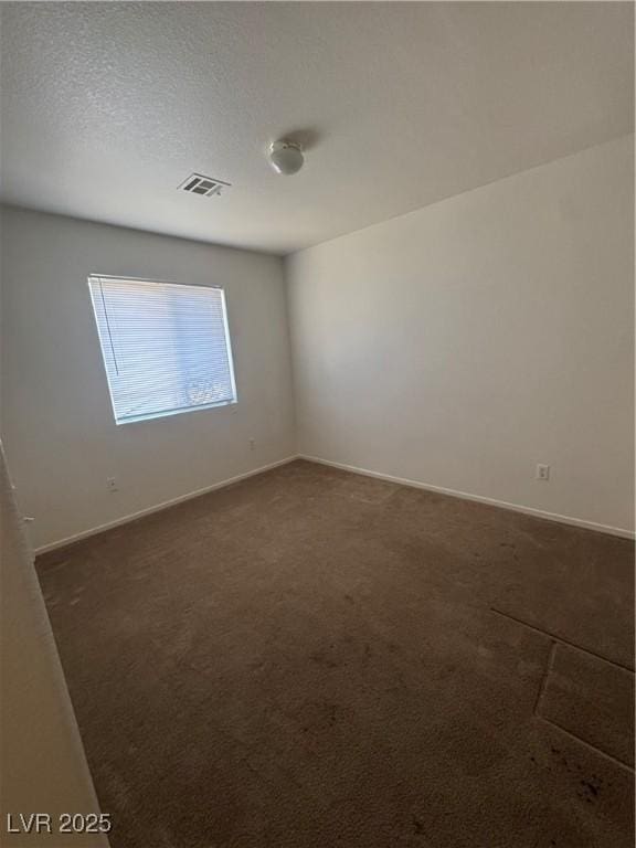empty room featuring baseboards, dark colored carpet, and visible vents