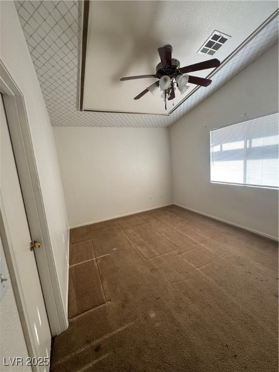 unfurnished room with ceiling fan, visible vents, baseboards, lofted ceiling, and carpet flooring