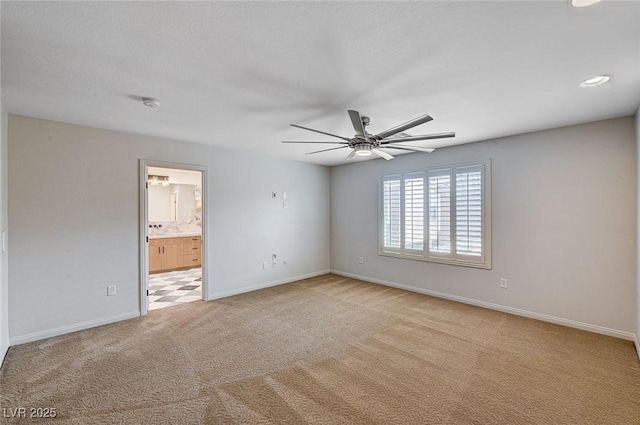 spare room featuring ceiling fan, light colored carpet, and baseboards