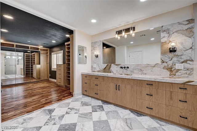 full bath with vanity, baseboards, tasteful backsplash, visible vents, and electric panel