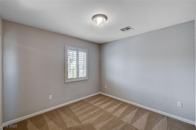 carpeted spare room featuring baseboards and visible vents