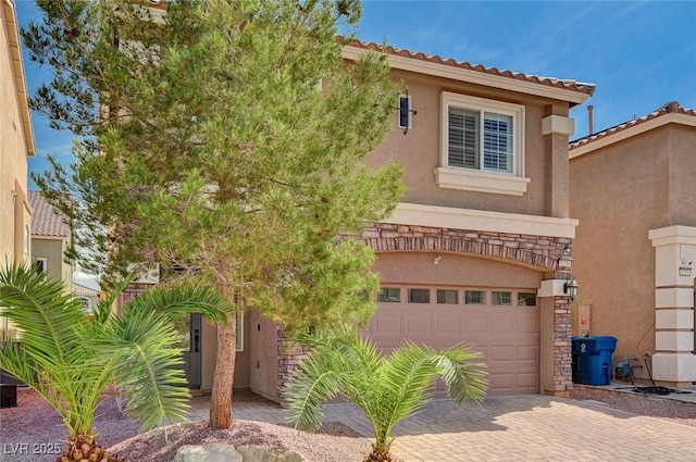 view of front of house featuring stucco siding, decorative driveway, a tiled roof, and a garage