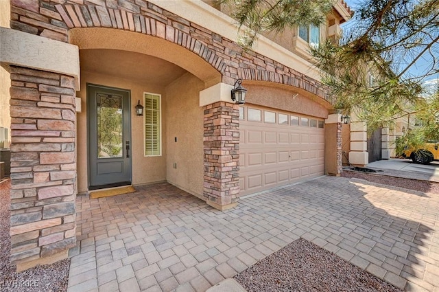 entrance to property with stucco siding, driveway, and stone siding