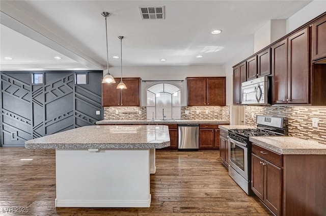 kitchen with dark wood-style flooring, stainless steel appliances, visible vents, and light countertops
