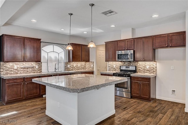 kitchen with a sink, dark wood-style flooring, tasteful backsplash, and stainless steel appliances
