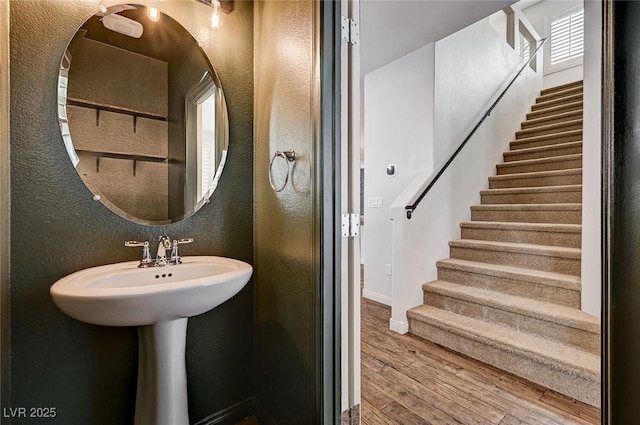 bathroom featuring baseboards, a textured wall, and wood finished floors