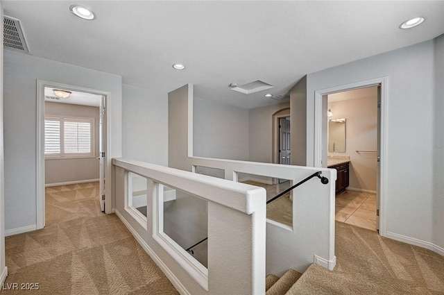 corridor featuring visible vents, baseboards, recessed lighting, carpet, and an upstairs landing