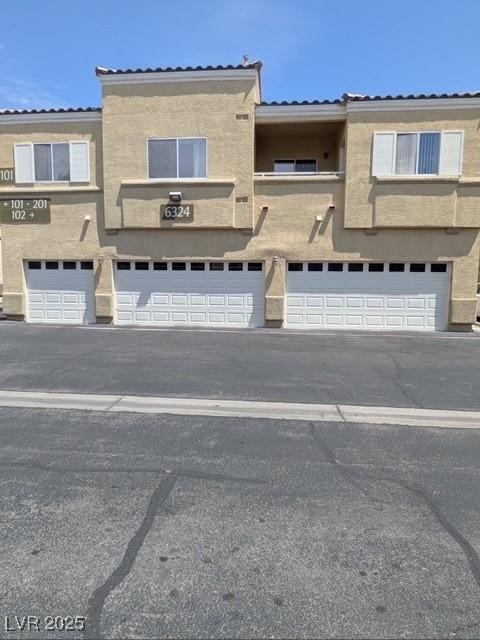 townhome / multi-family property featuring a garage, stucco siding, and driveway