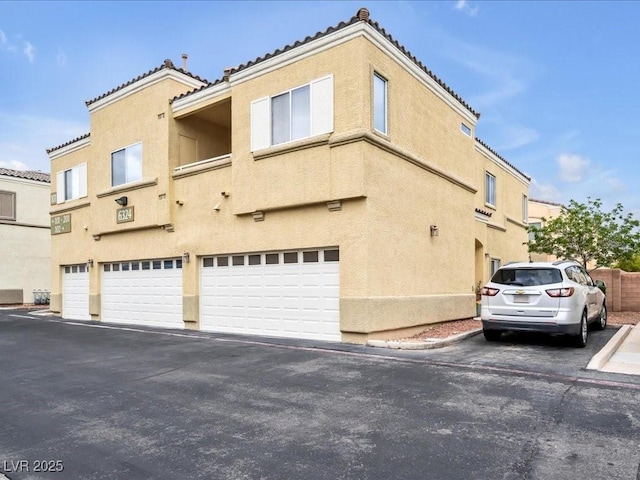 6324 Desert Leaf St Unit 3, North Las Vegas, NV 89081 - view of property exterior with a tile roof, an attached garage, stucco siding, and driveway