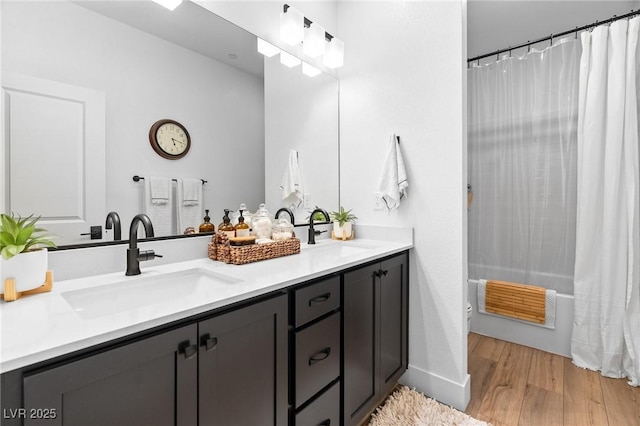 full bath with wood finished floors, shower / tub combo, vanity, baseboards, and toilet