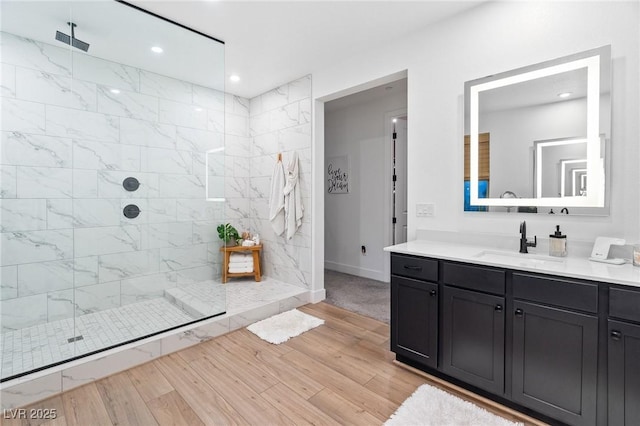 full bathroom featuring vanity, wood finished floors, baseboards, recessed lighting, and a walk in shower