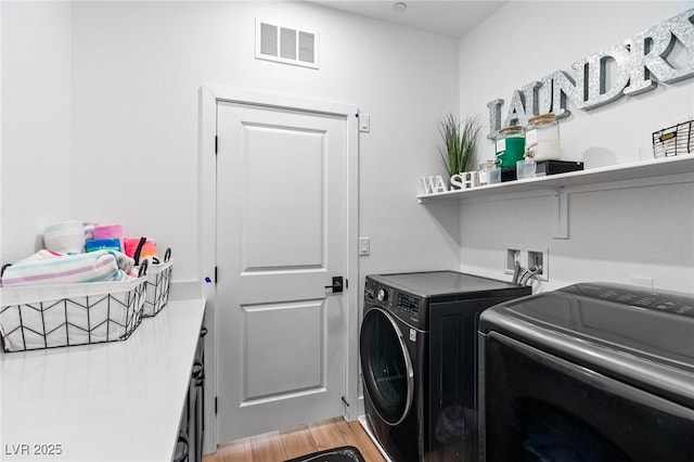 laundry room with laundry area, light wood-style floors, separate washer and dryer, and visible vents