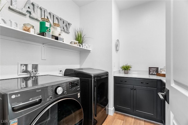 laundry room with light wood-style floors, cabinet space, and washing machine and clothes dryer