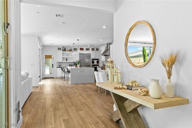 hall featuring recessed lighting, a sink, visible vents, and light wood-style flooring