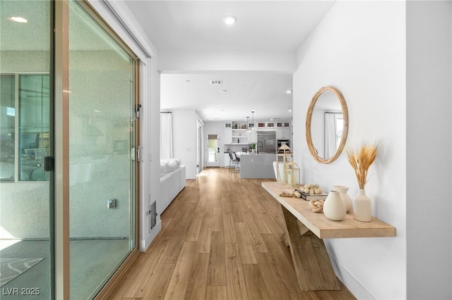 hallway featuring light wood-type flooring, recessed lighting, and visible vents