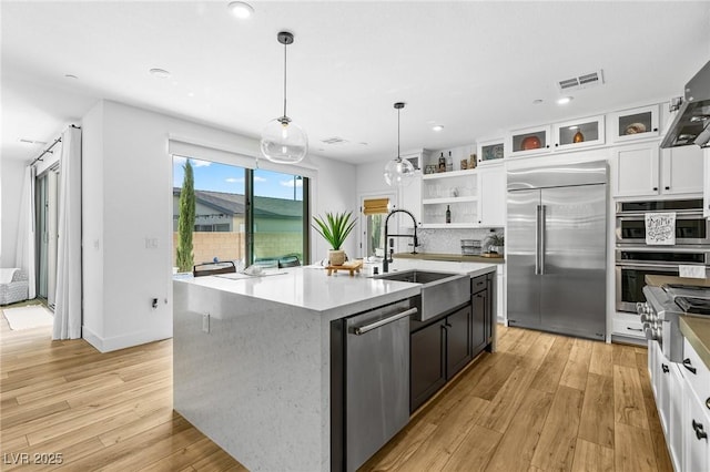 kitchen with white cabinets, open shelves, appliances with stainless steel finishes, a sink, and visible vents