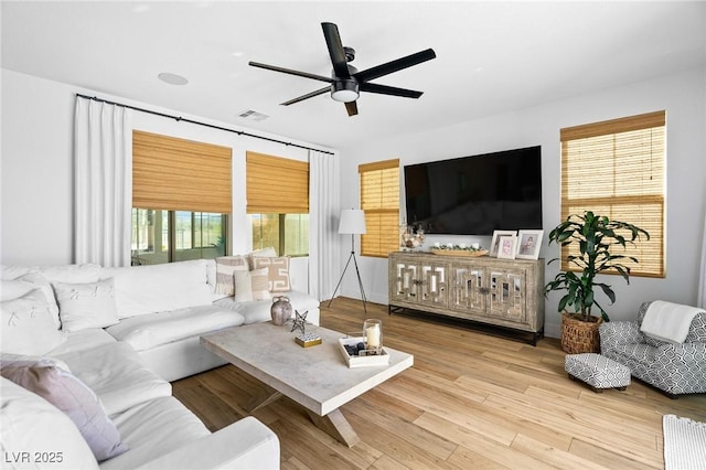 living area with a ceiling fan, wood finished floors, and visible vents