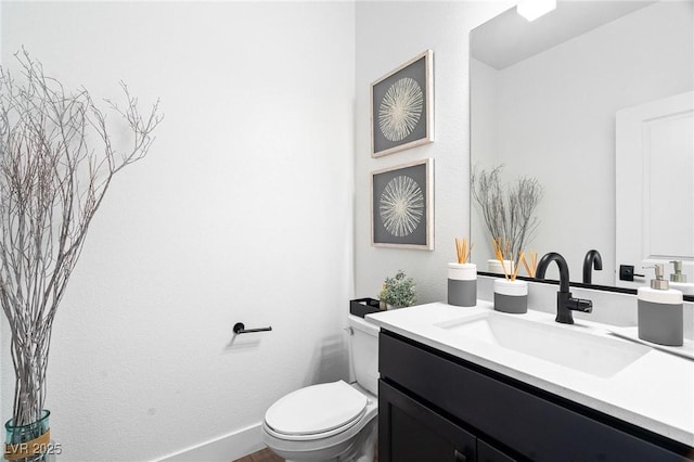 half bath featuring toilet, baseboards, and vanity