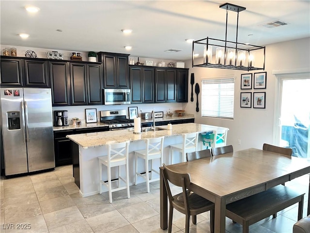 2585 Amazing Meadows Ave Unit 1007, North Las Vegas, NV 89031 - kitchen featuring dark cabinetry, a kitchen island with sink, visible vents, and appliances with stainless steel finishes