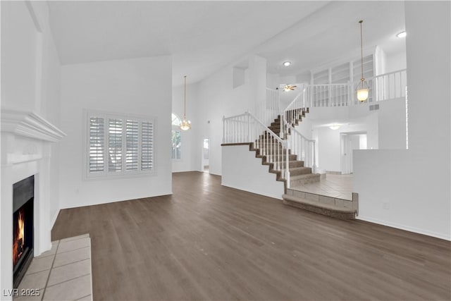 2808 Deep Water Cir, Las Vegas, NV 89117 - unfurnished living room with high vaulted ceiling, a lit fireplace, wood finished floors, stairs, and ceiling fan