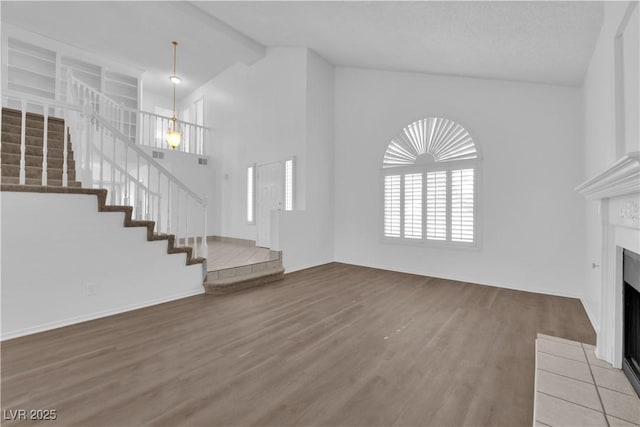 2808 Deep Water Cir, Las Vegas, NV 89117 - unfurnished living room featuring wood finished floors, a fireplace with flush hearth, stairway, and high vaulted ceiling