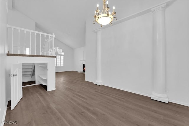 2808 Deep Water Cir, Las Vegas, NV 89117 - unfurnished living room with wood finished floors, a chandelier, a warm lit fireplace, high vaulted ceiling, and decorative columns