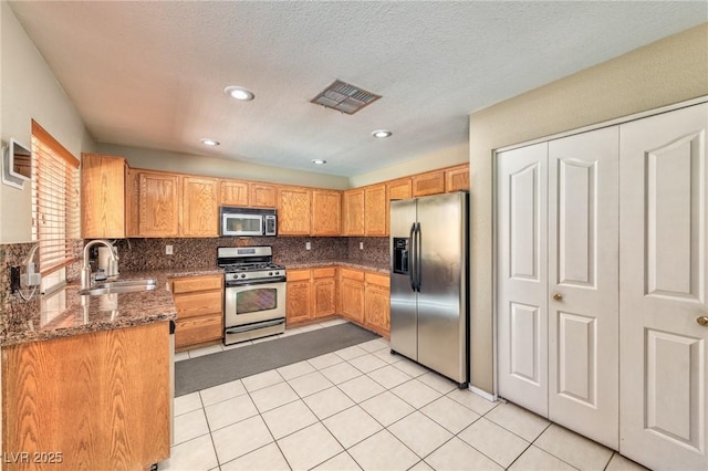 7751 Locke Haven Dr, Las Vegas, NV 89123 - kitchen with appliances with stainless steel finishes, a sink, tasteful backsplash, light tile patterned floors, and dark stone counters