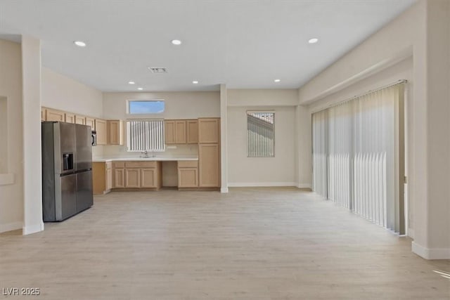 kitchen featuring stainless steel fridge, light wood-style flooring, baseboards, and light brown cabinets