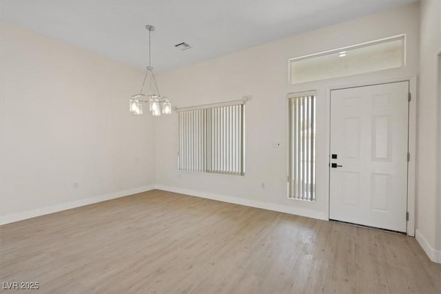 foyer entrance featuring baseboards, visible vents, wood finished floors, and a notable chandelier