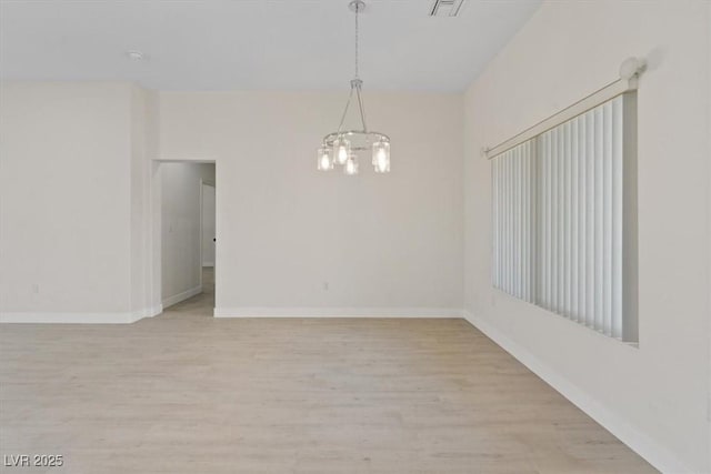 spare room featuring baseboards, a chandelier, and light wood finished floors