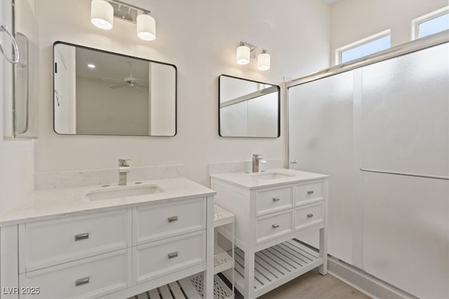 bathroom with a sink, a shower stall, and two vanities