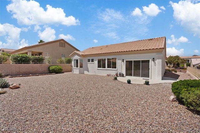 back of property featuring a patio, stucco siding, a tile roof, and fence
