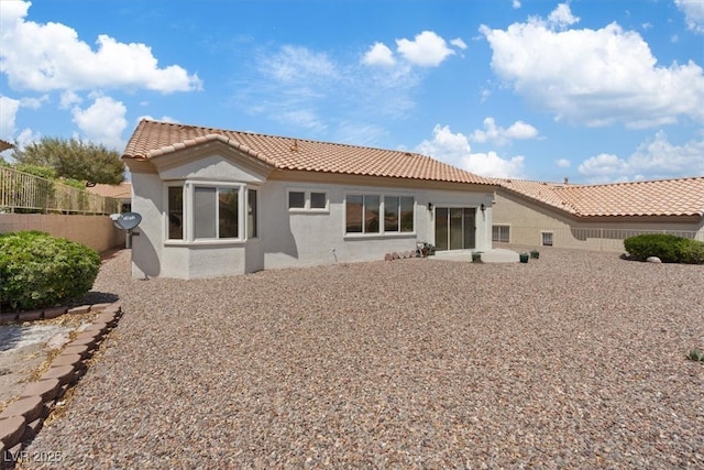 back of property featuring a tiled roof, fence, and stucco siding