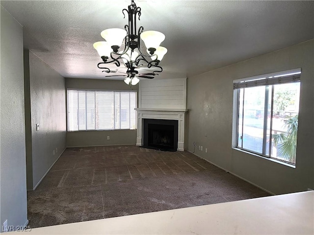 unfurnished living room with a fireplace, carpet floors, a textured ceiling, a chandelier, and baseboards