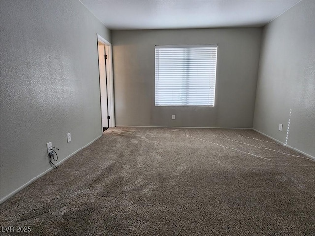 carpeted empty room featuring baseboards and a textured wall