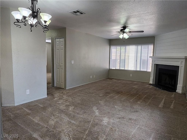 unfurnished living room featuring a textured ceiling, a large fireplace, carpet, ceiling fan with notable chandelier, and visible vents
