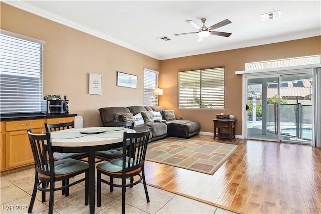 dining room with crown molding, light wood-style floors, visible vents, and a ceiling fan