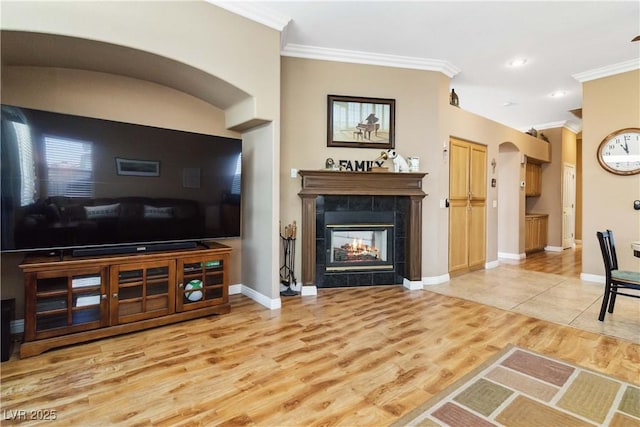 living area featuring light wood-type flooring, baseboards, a fireplace, and ornamental molding