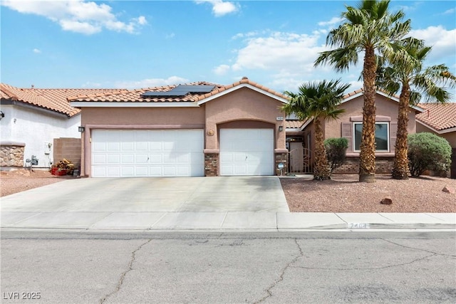 mediterranean / spanish-style house with an attached garage, roof mounted solar panels, a tiled roof, stucco siding, and concrete driveway