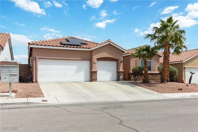 mediterranean / spanish-style house with concrete driveway, stucco siding, a garage, and roof mounted solar panels