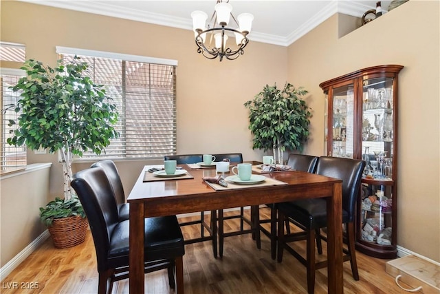 dining room with a chandelier, wood finished floors, baseboards, and ornamental molding