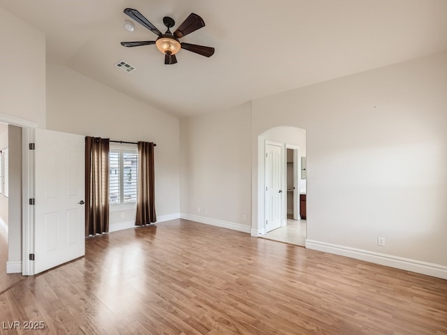 spare room with ceiling fan, light wood finished floors, arched walkways, baseboards, and visible vents