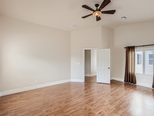 empty room featuring light wood-style floors, high vaulted ceiling, ceiling fan, and visible vents