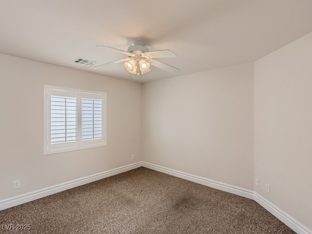 spare room featuring dark colored carpet, a ceiling fan, baseboards, and visible vents