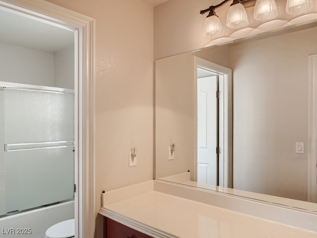 full bath with vanity, combined bath / shower with glass door, and toilet