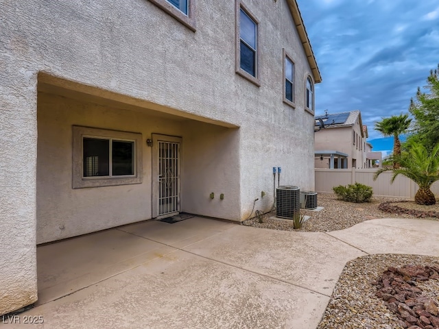 rear view of house featuring fence, central AC unit, a patio area, and stucco siding