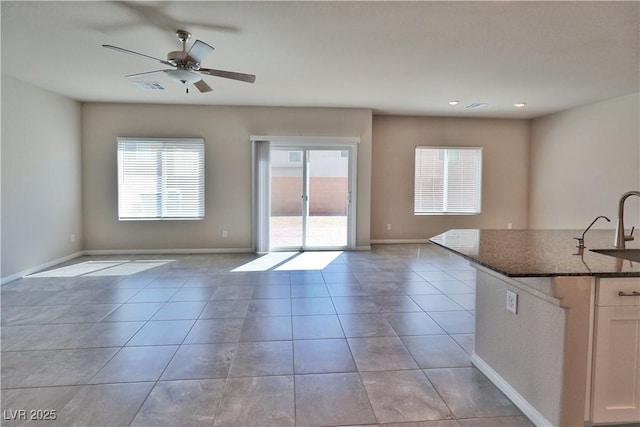 interior space featuring a healthy amount of sunlight, light tile patterned floors, a ceiling fan, and a sink