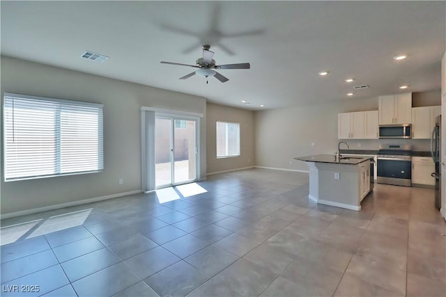 kitchen featuring dark countertops, a sink, stainless steel appliances, open floor plan, and visible vents